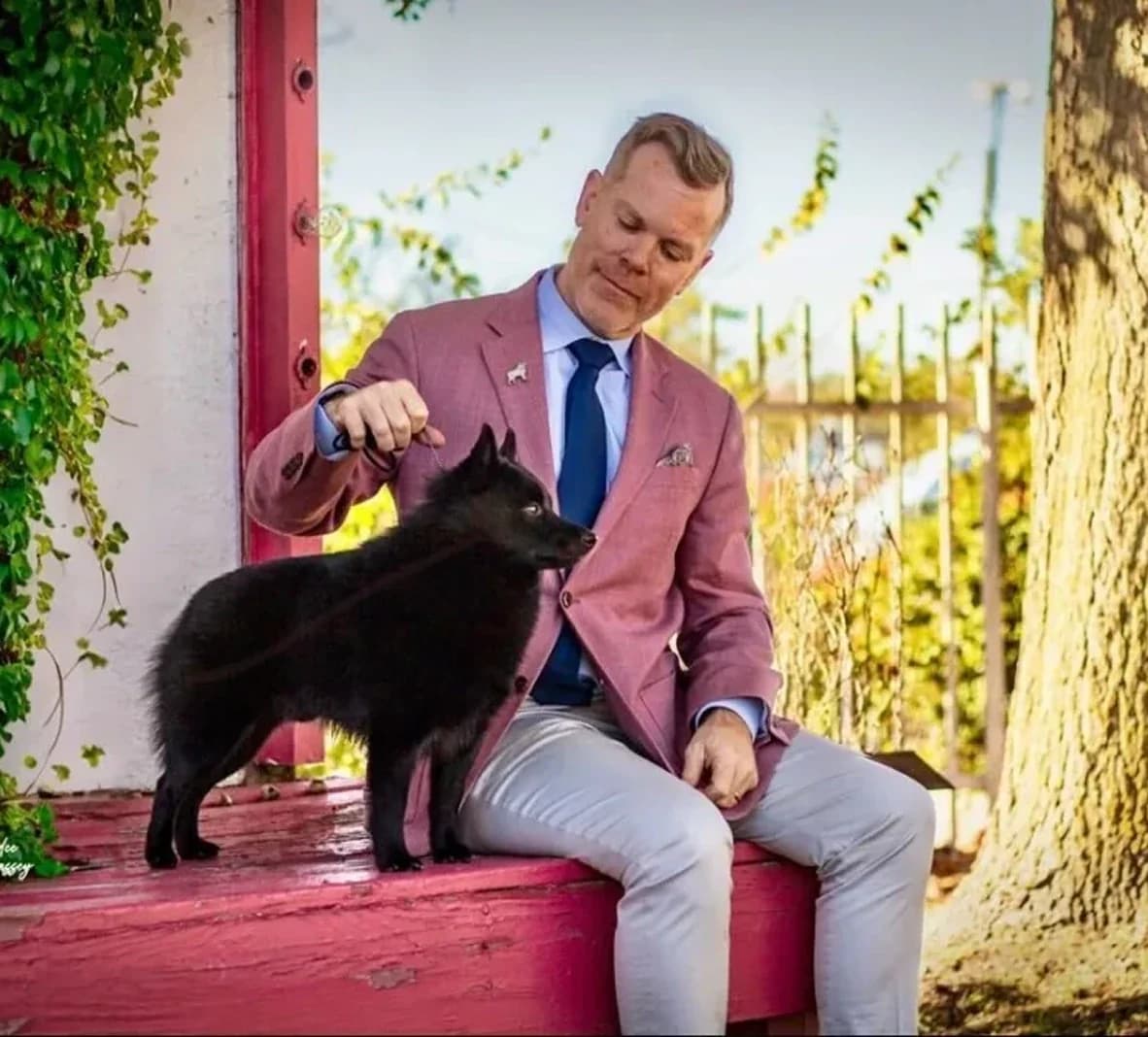 Matthew G. Stroud sitting on a porch with his black Schipperke.